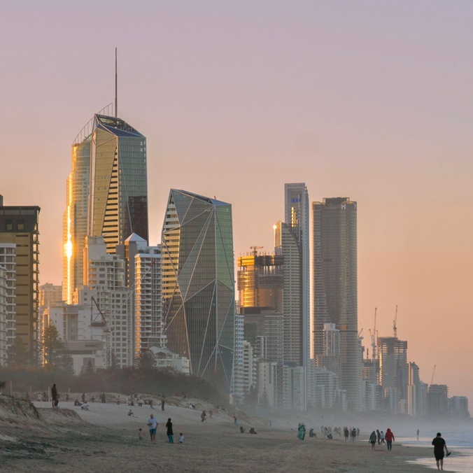 An eroded beach with skyscrapers in the background on the coastal fringe.