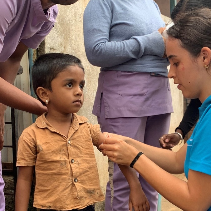 A nursing student measuring a boy's arm