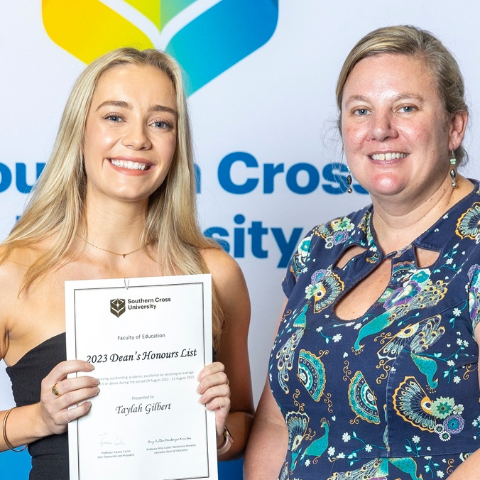 Two women facing the camera, one holding a certificate