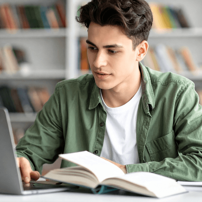Student reading textbook and working on laptop - postgrad events banner