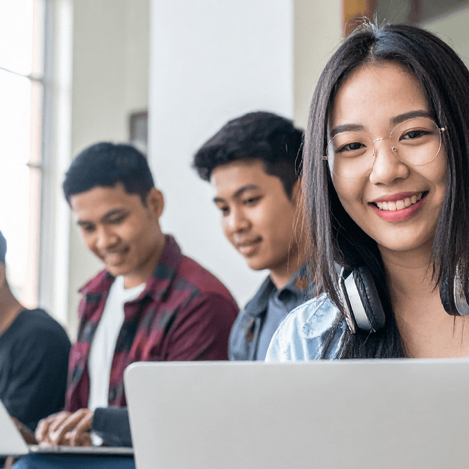 A group of smiling international students working on laptops - for postgrad workshop events