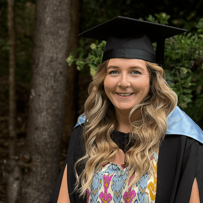 Woman in graduation robes and mortarboard