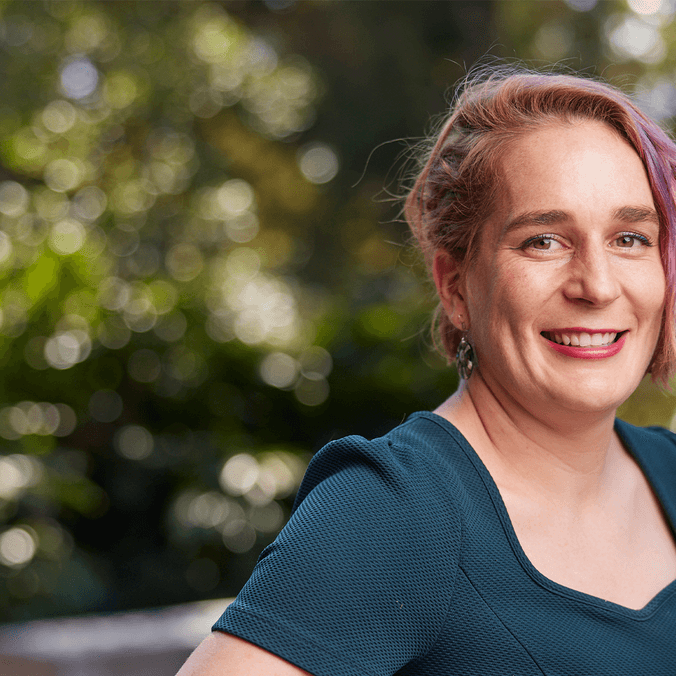 Woman in green shirt smiling with greenery in background