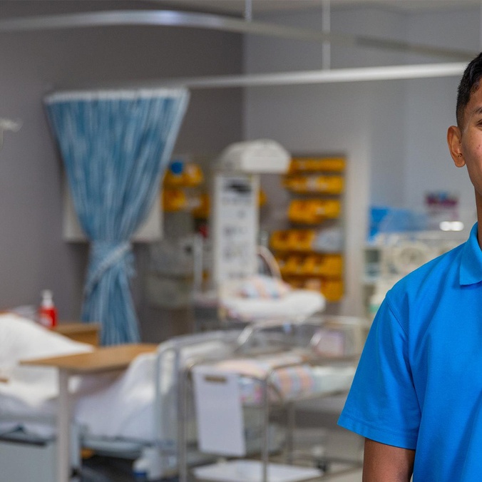 Student in nursing lab with sim doll in hospital bed