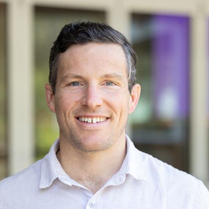 Headshot of man in button up shirt smiling at camera
