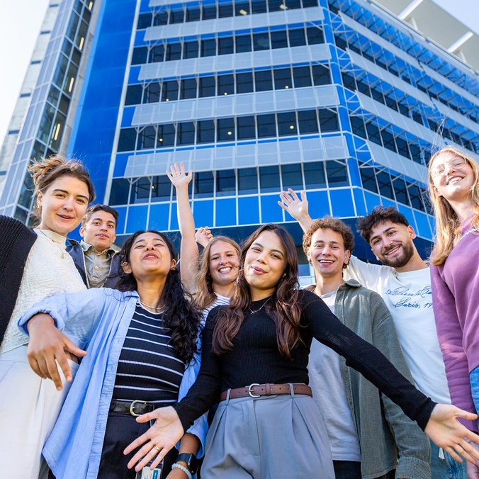 Group of students posing in front of blue building