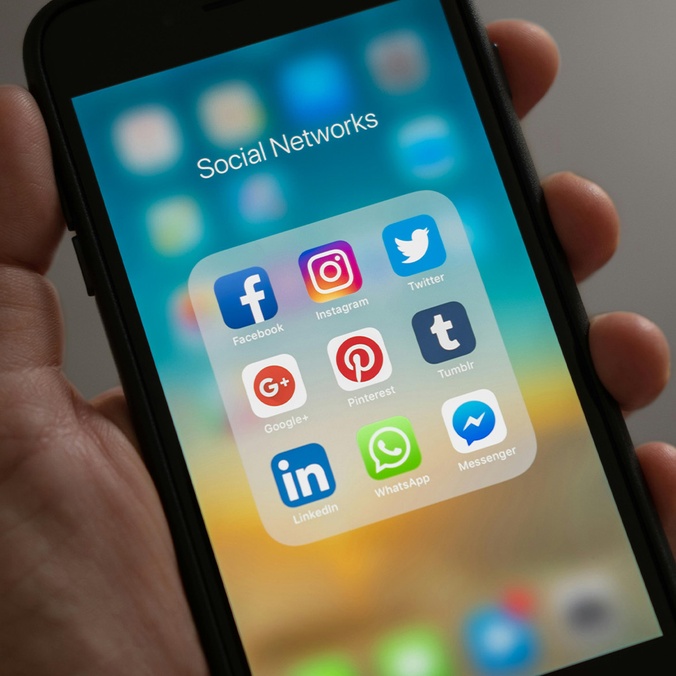 Hand holding phone with social media apps
