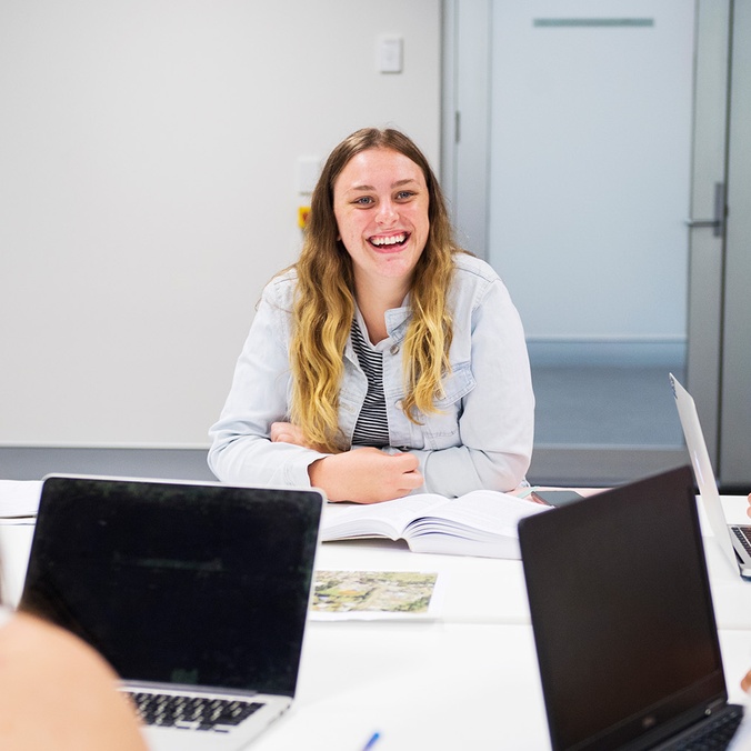 Student smiling in group with laptops
