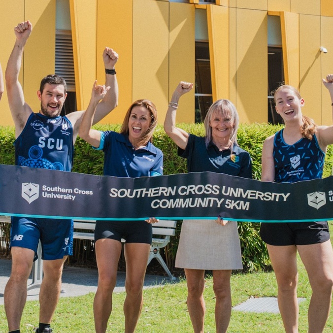 A group of people hold a banner advertising the GC50 Run Festival