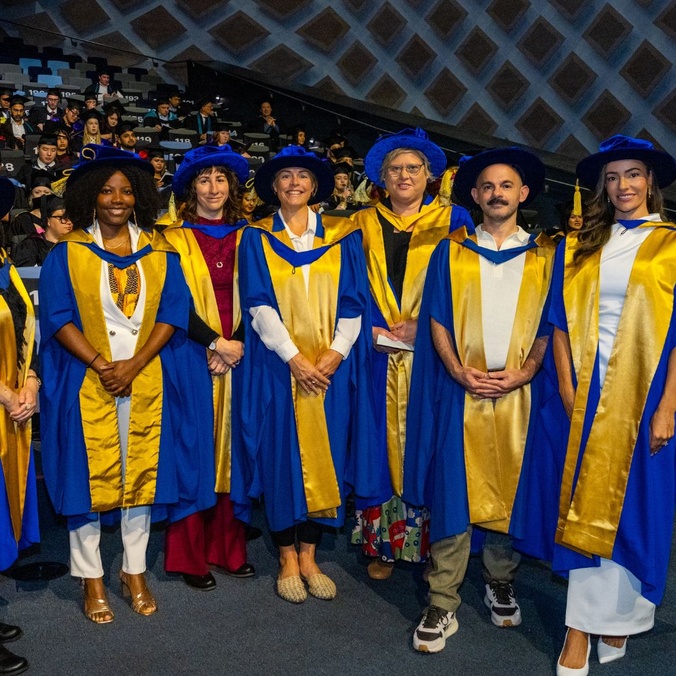 Men and women in graduation robes smiling at camera