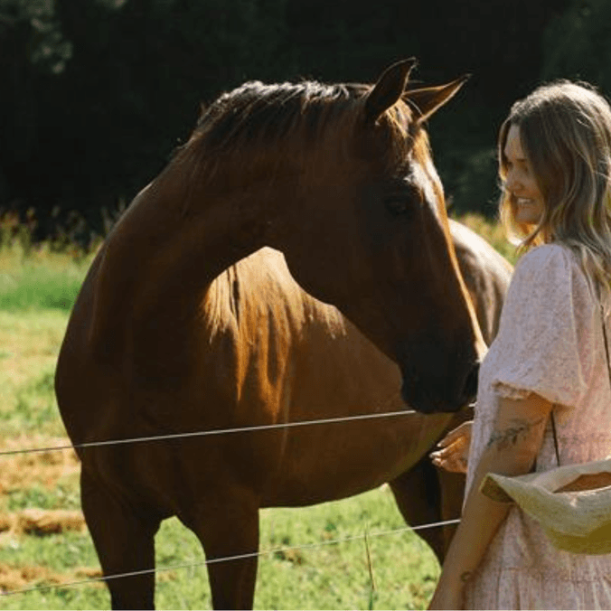 A woman, Scarlett Austin, stands beside a horse