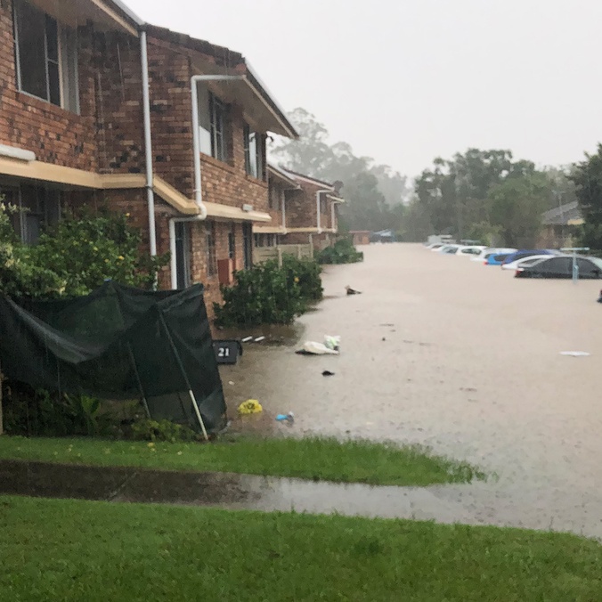 A flooded street with unit blocks and cars underwater