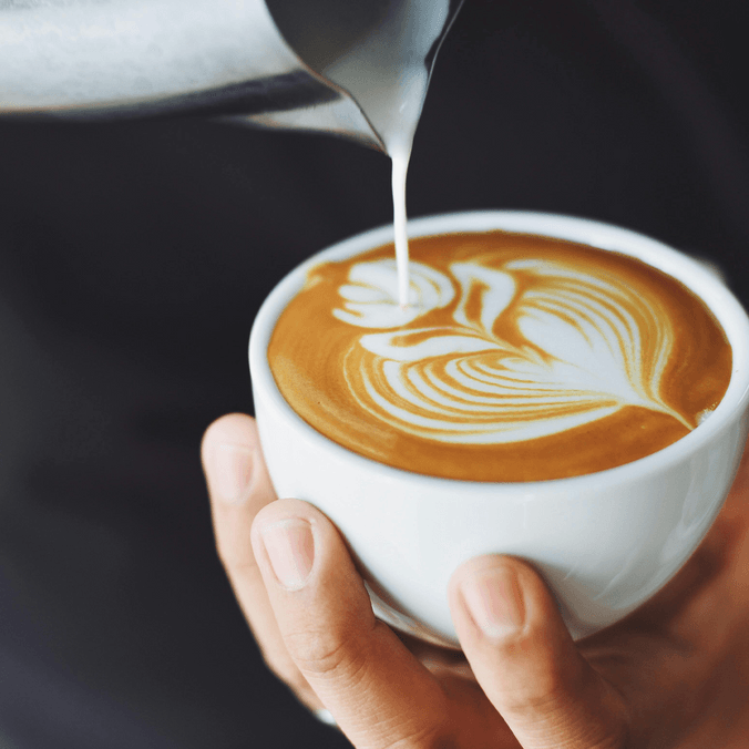 Frothed milk being poured into cup of coffee