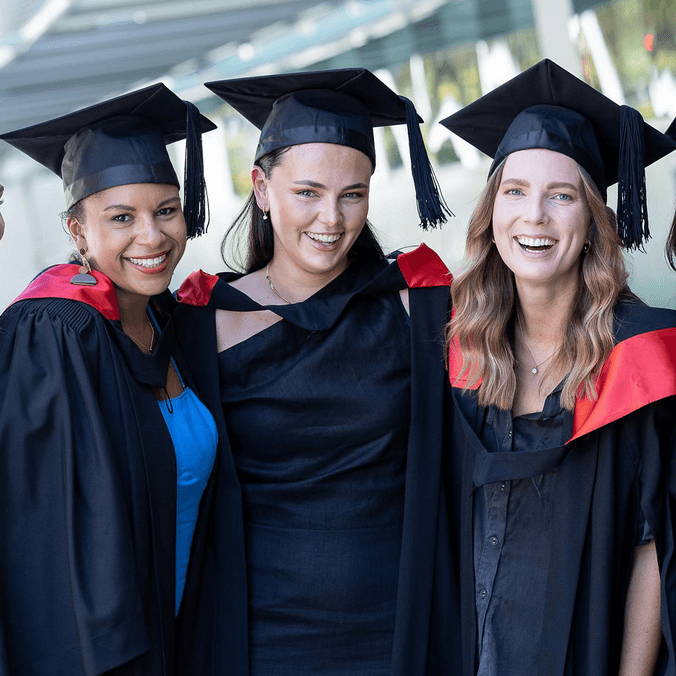 Group of students in graduation robes and mortarboards smiling at camera