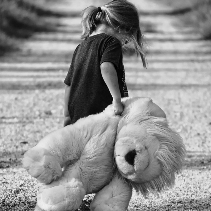 Girl holding plush toy on a dirt road