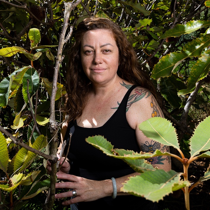Woman with arm tattoos in a bush setting