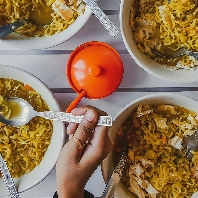 Close-up of a person getting noodles from four different bowls