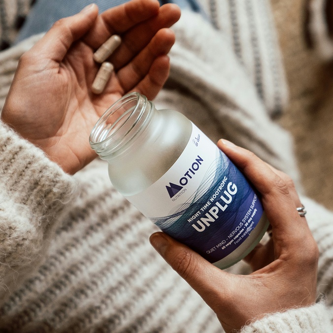 A woman's hands holding a bottle containing health supplements