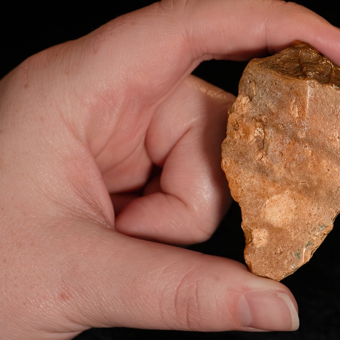 Close up of a hand holding stone tools