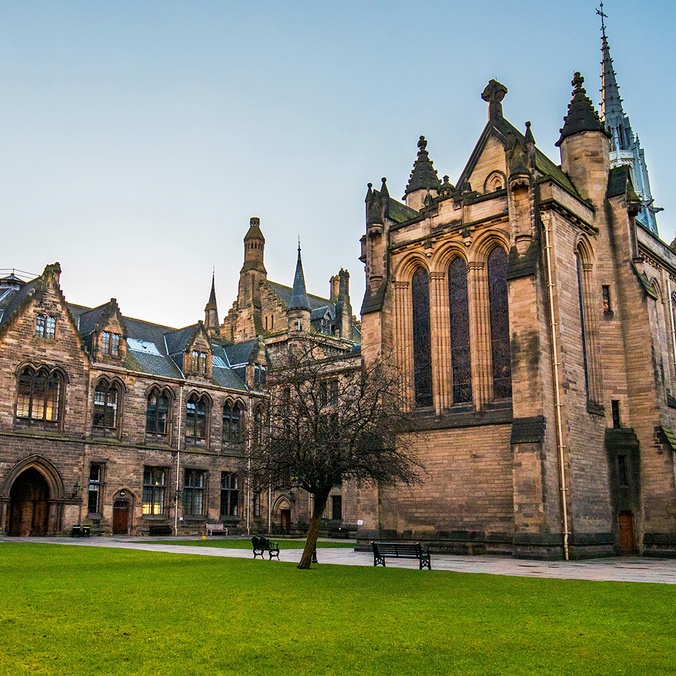 Exterior of a sandstone university with a grass lawn