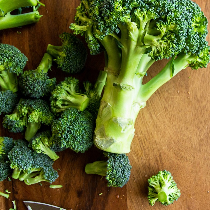 Broccoli on chopping board with a knife