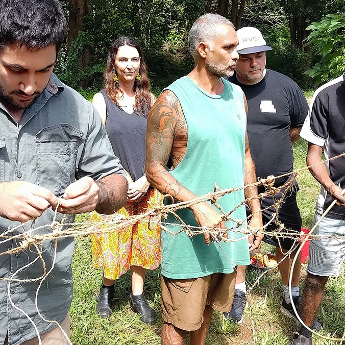 Indigenous men making a net using plant fibres
