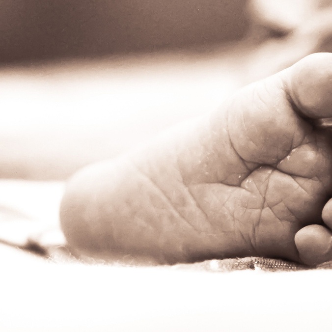 Monochrome close-up of a newborn's delicate foot on a soft surface