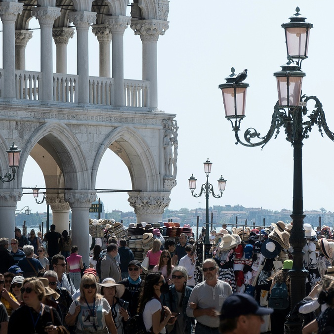 A bustling city square filled with people overlooking a waterway