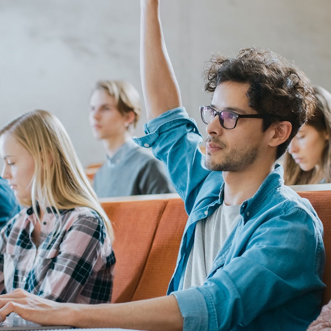 a student in a class with his hand up