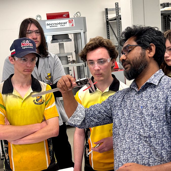 A group of school students and researcher in engineering lab