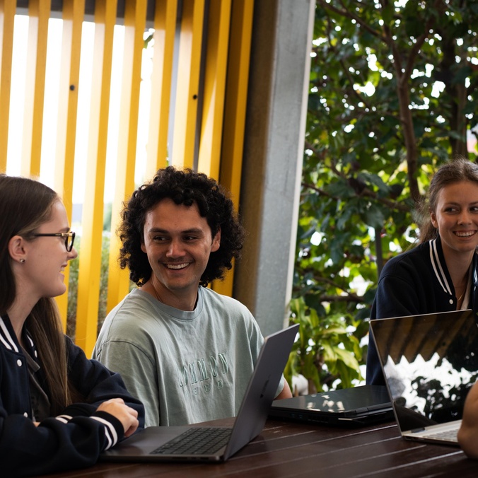 Group of students smiling around laptops