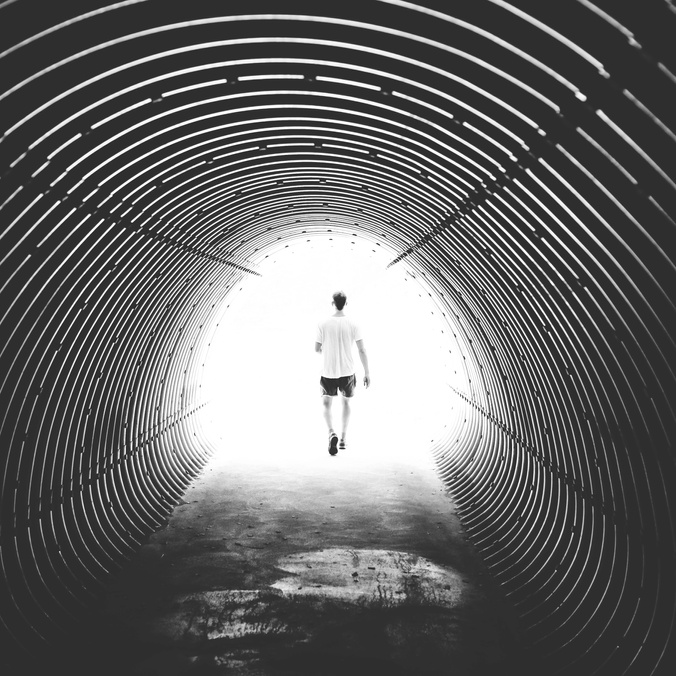 A silhouetted figure at the end of a dark tunnel