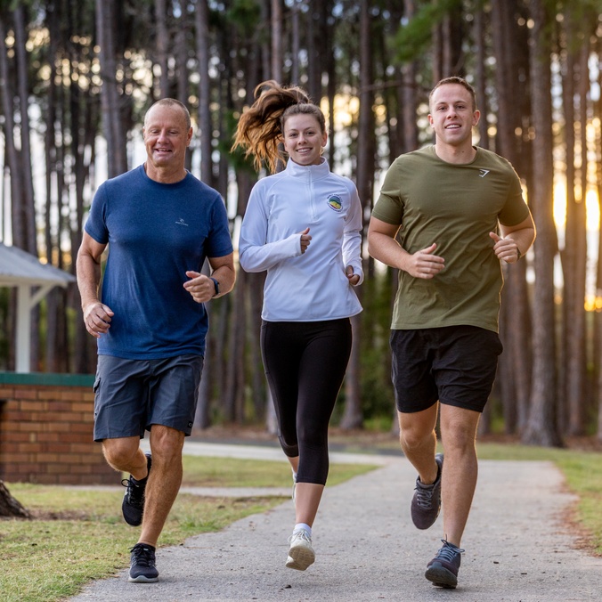 Three adults running in a park