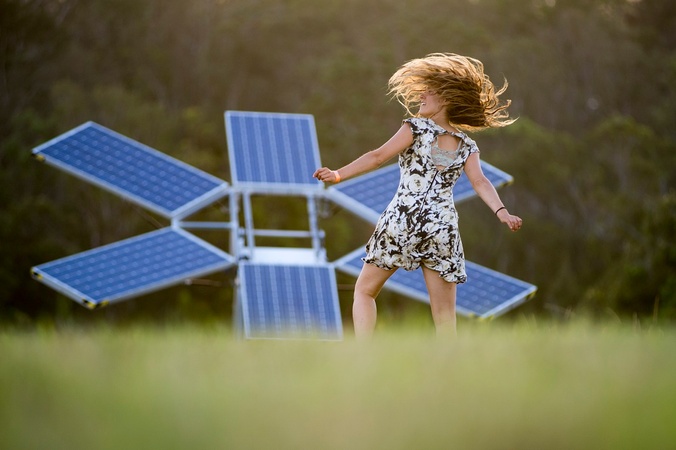 Woman dancing in front of solar panels. Image courtesy Woodford Folk Festival