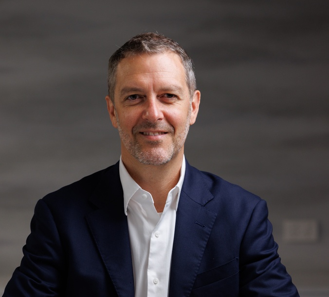Headshot of a man wearing a white shirt and a blue jacket