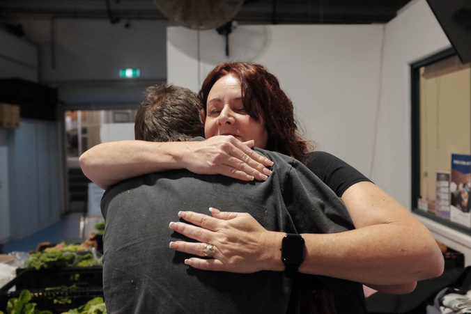 Alumni Theresa hugs member of community