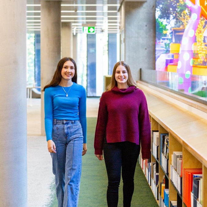 Two students walking in library