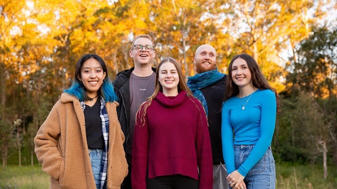 5 students standing in front of trees