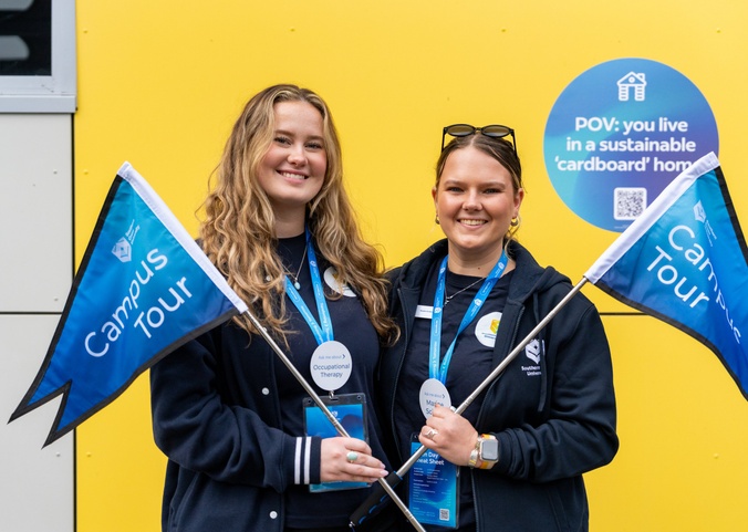 Two female students holding campus rous flags