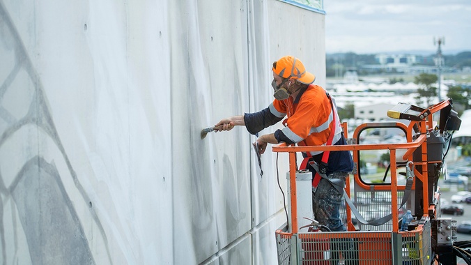 Man wearing high visibility safety gear on crane painting large artwork | Guido van Helten