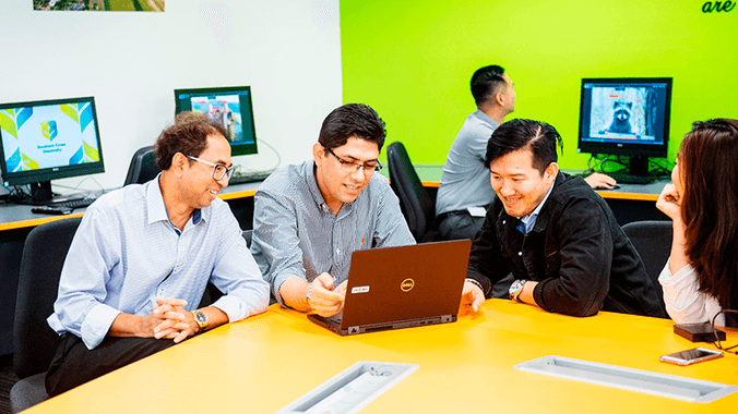 Several students sitting around a table looking into a laptop