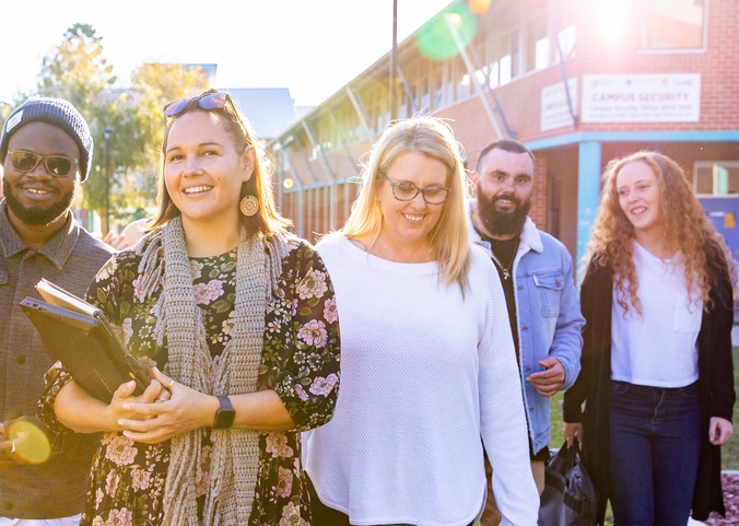 A group of education students, dylan berger, genna guy, hansika badhuge, jane hosking, kirsten atkinson, mandy atkinson, marius odiachi, nathan lancaster walking with the sun shining through the group at the Southern Cross University Coffs Harbour Campus