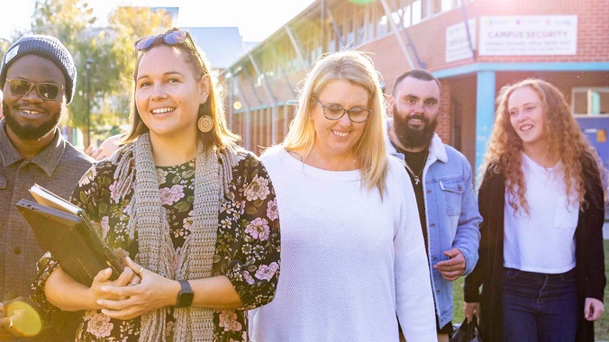A group of education students, dylan berger, genna guy, hansika badhuge, jane hosking, kirsten atkinson, mandy atkinson, marius odiachi, nathan lancaster walking with the sun shining through the group at the Southern Cross University Coffs Harbour Campus
