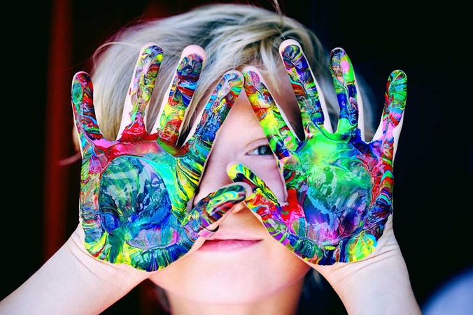 Boy smiling at camera with painted hands