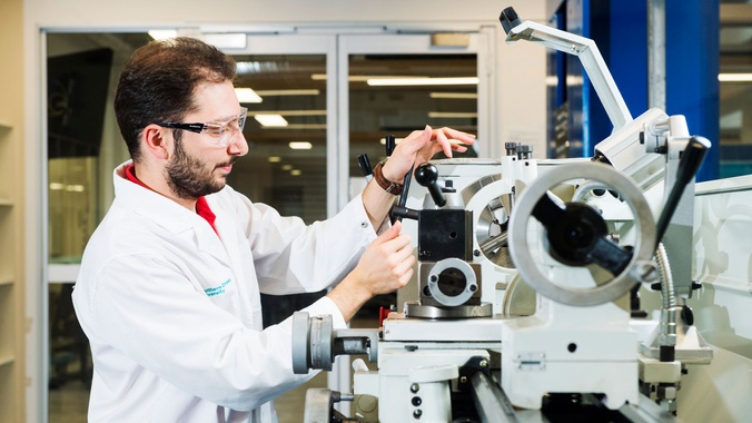 Male mechanical engineering student in lab using engineering research equipment