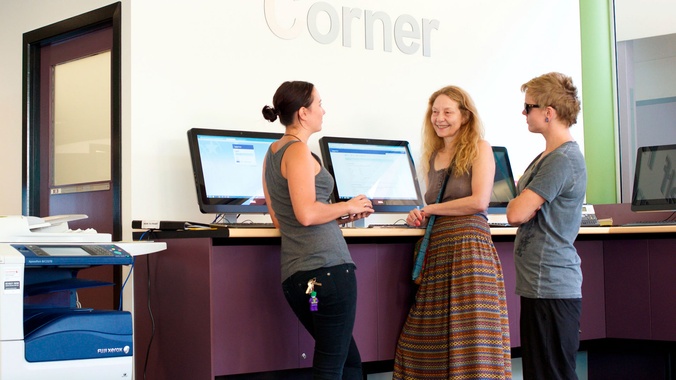 Three people talking while standing in the self help corner