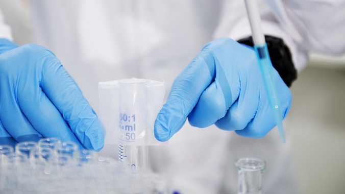 Close up of researcher wearing blue latex gloves preparing test tube samples in a laboratory setting