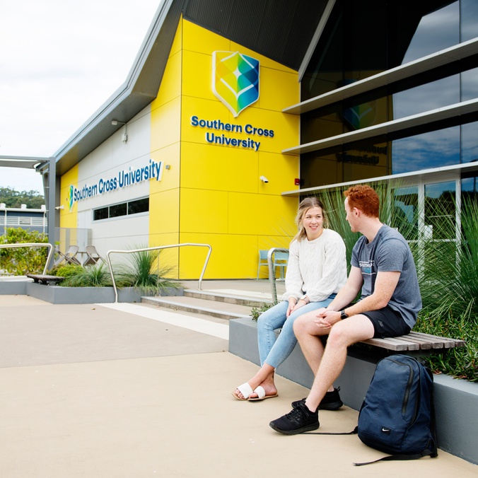 Two student sitting outside the Health Sciences building at the Coffs Harbour campus