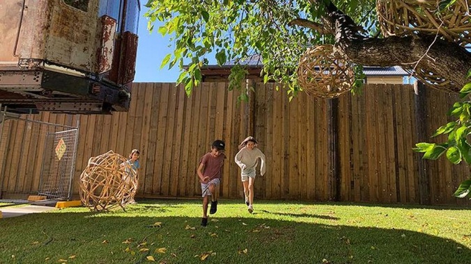 2 children running across a fenced off yard