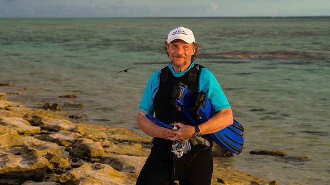 Distinguished Professor Peter Harrison stands on a beach